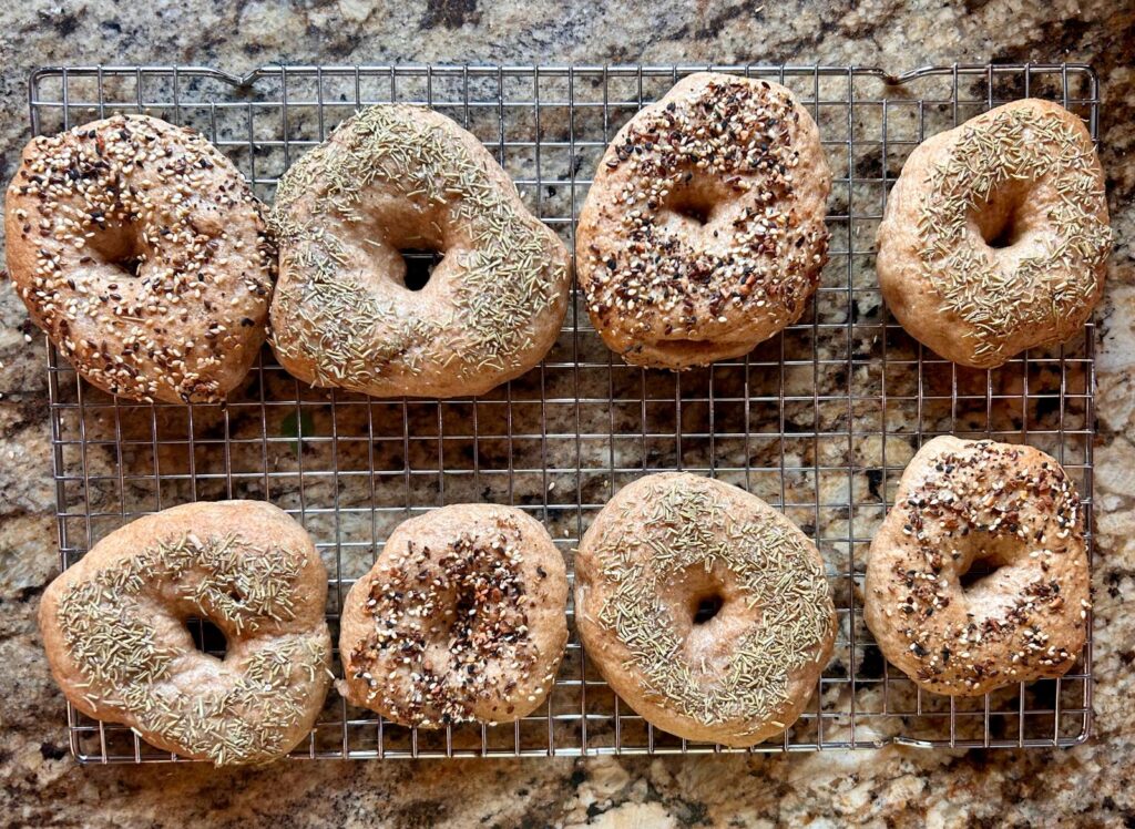 8 boiled, seasoned and baked bagels on a cooling rack, ready to serve.