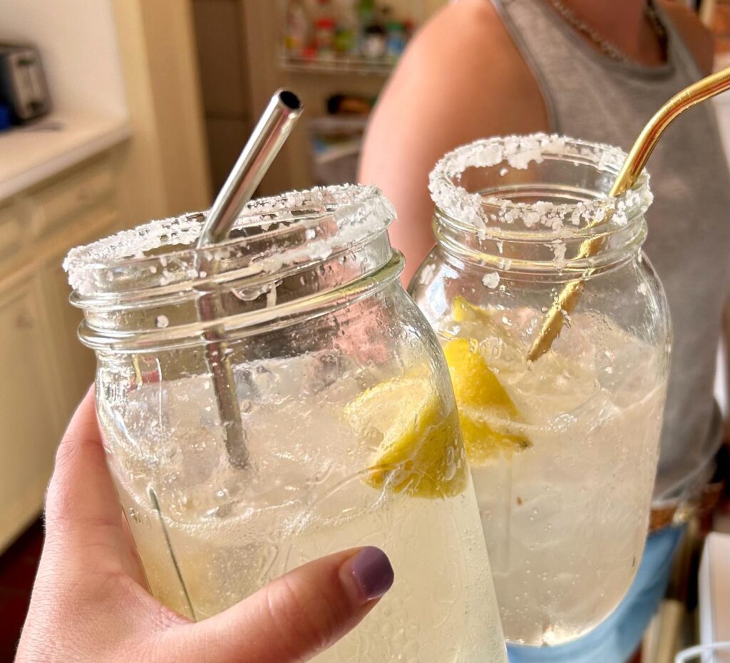 This is an image of two people clinking their drinks together. The drinks are chiltons served in a mason jar with a salthed rim.