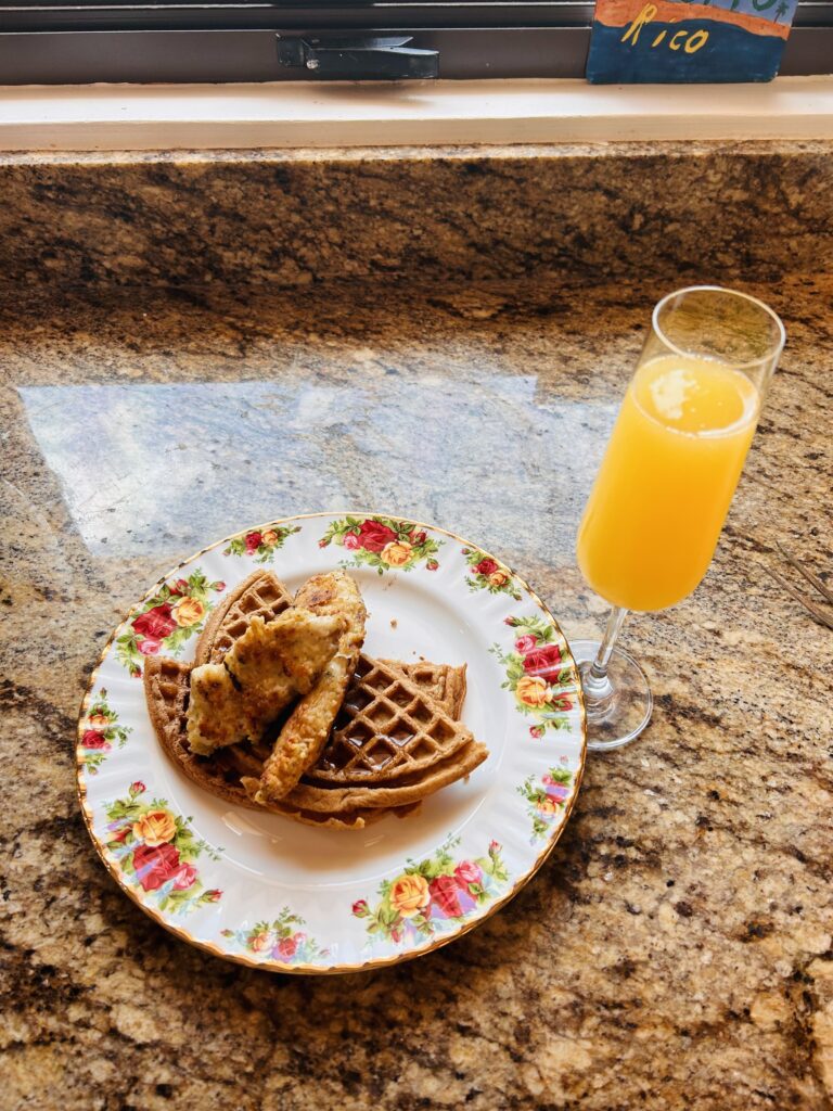 Chicken and Waffles from the cow and girl recipe stacked on a plate and ready to be served as the perfect brunch with a mimmosa. Birds recipe