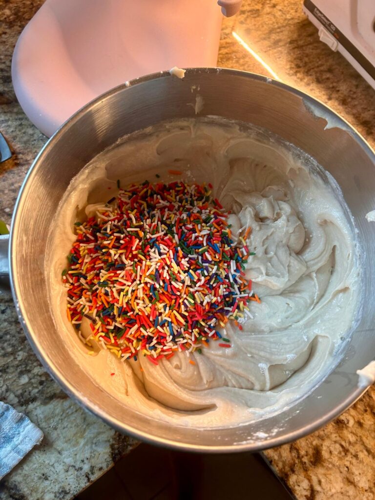 Cake batter with lots of sprinkles that are about to be folded into batter to creat the confetti look in the confetti cake.