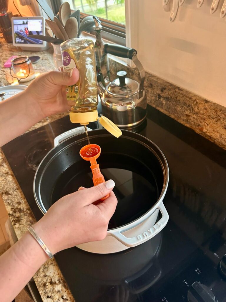 This is an image of someone adding honey yo a pot of water that will be used for boiling the bagels.