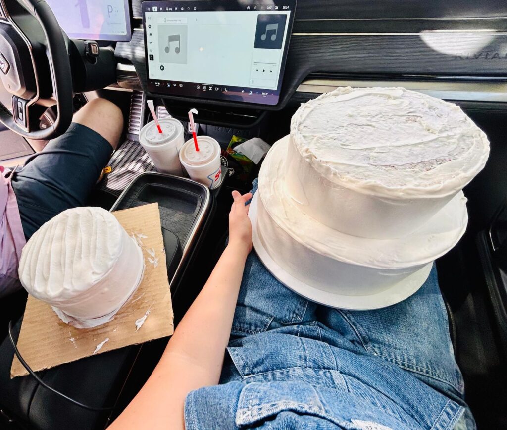 This is an image of a deconstucted three tier wedding cake that is being transported in the car. This cake is covered in white chream cheese icing.