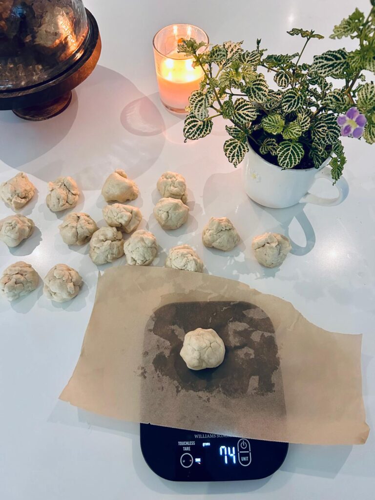 This image features sourdough tortilla dough being divided into equal parts weighing 74 grams so they are prepared to be rolled into equal sized tortillas.